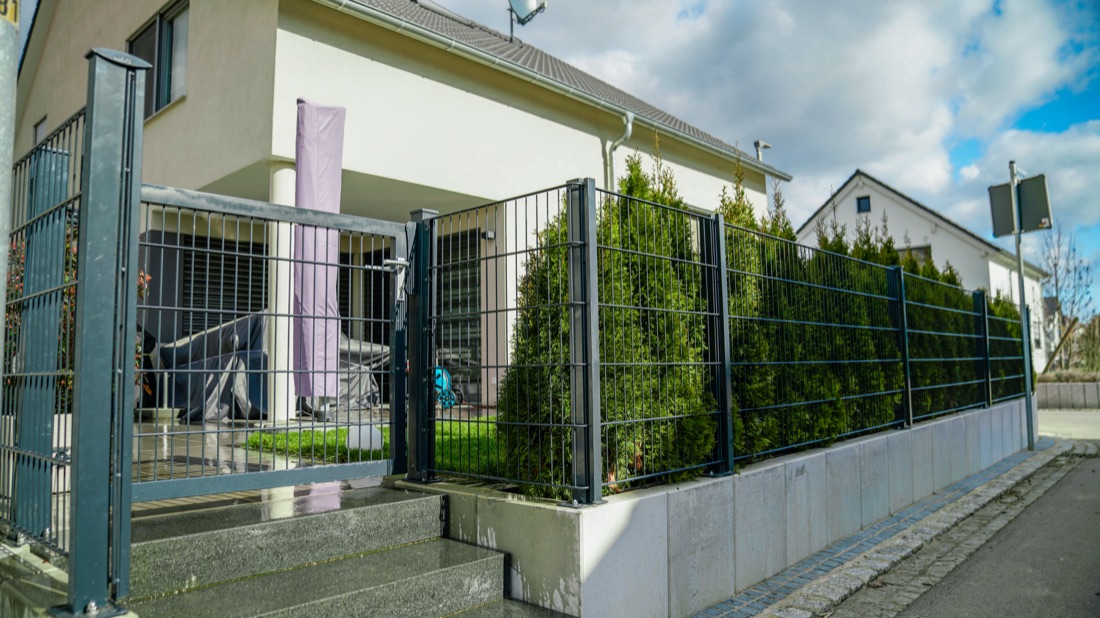 Zaun aus Doppelstabmatten auf einer Sockelmauer aus Beton, dahinter die Säulenhecke, Benningen
