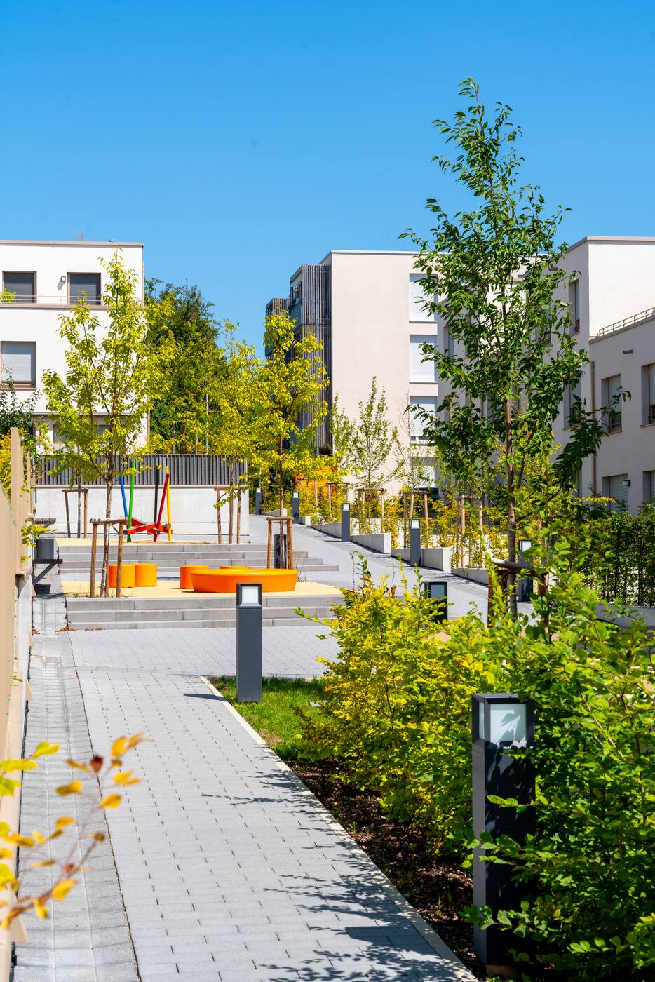 Fertige Anlage mit Weg, Bepflanzung und Spielbereich zwischen den Gebäuden