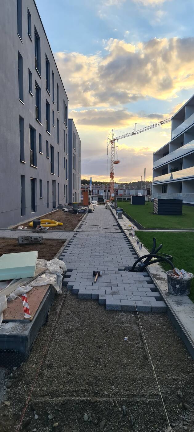 Wegebau in einer Wohnanlage während der Arbeiten: frisch verlegtes Pflaster zwischen den Gebäuden